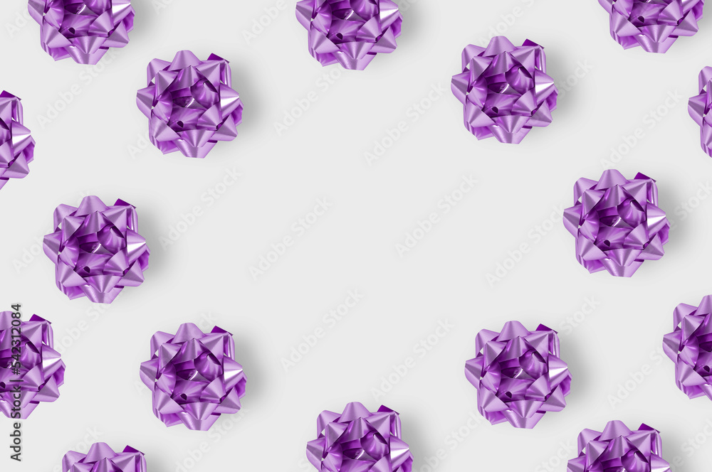 Minimal composition background of plastic purple decorative Christmas gift bows. New Year concept.Place for the inscription