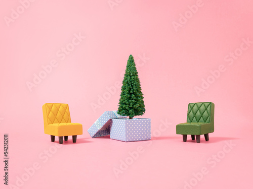Christmas composition. Yellow and green armchair, Christmas tree with presents on pink background. Winter holidays, new year minimal concept.