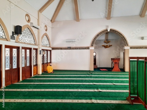 A male worshiper prays alone in an empty mosque photo