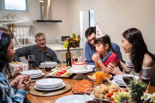 Multi-ethnic big family having a birthday party for young kid daughter. 