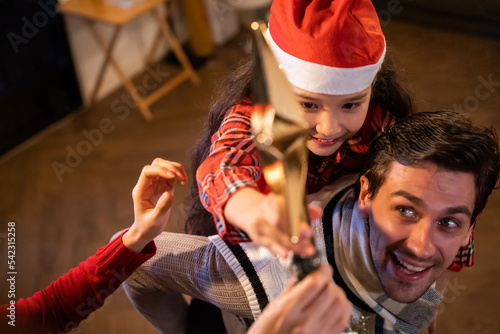 Caucasian couple and young daughter decorating Christmas tree at home.
