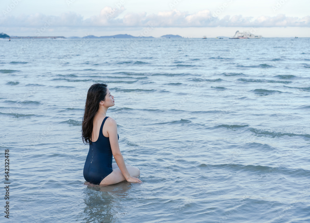 woman kneels in shallow seawater