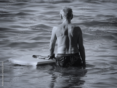 Photos old man / retired man at the sea, holding a boogie board,  black and white photo