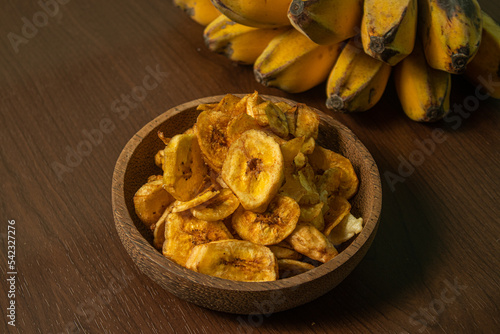 Crispy and delicious banana chips on a wooden background