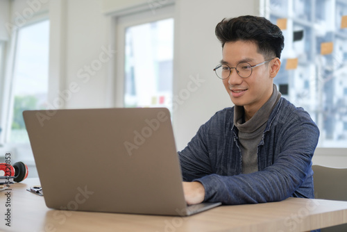 Stylish man freelancer using laptop computer in bright modern office.