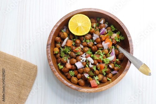High in protine boiled black chana or chickpea salad. Chopped tomatoes, onion, chilies, and coriander mixed with boiled chickpea or Bengal gram. Weight loss meal. Served with Lemon. Copy space.