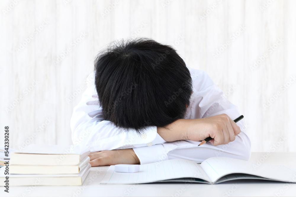 机に頭を伏せる子供―勉強をしたくないイメージ 机に頭を伏せる子供―勉強をしたくないイメージ