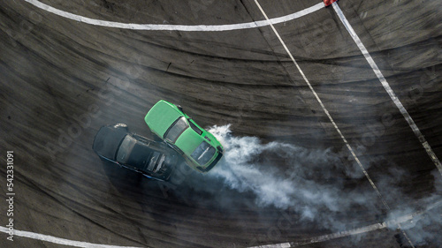 Aerial top view car drifting, Race drift car with lots of smoke from burning tires on speed track, Two car drifting battle on asphalt race track, Two drift cars battle with smoke from burned tire.