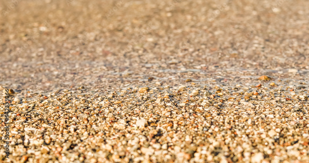 A background of sand, small pebbles and flowing wave on the sea beach. Summer vacation concept A background of sand, small pebbles and flowing wave on the sea beach. Summer vacation concept