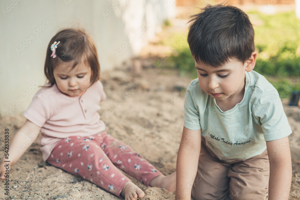 Sister and brother playing dirty soil on spring day in the garden. People lifestyle concept. Happiness concept. Family lifestyle concept. Family activity Sister and brother playing dirty soil on spring day in the garden. People lifestyle concept. Happiness concept. Family lifestyle concept. Family activity