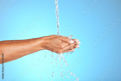 Hands, water and woman in studio for cleaning, washing hands and safety from bacteria against a blue background. Hand, splash and model washing for skincare, hygiene and germ prevention with mockup
