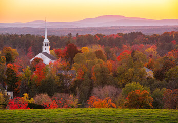 landscape of church tower in autumn mountain forest during sunset