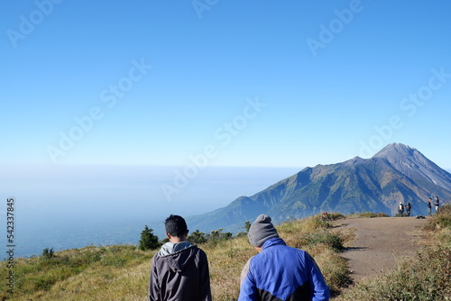 In the morning two people are enjoying the beauty of Mount Merapi from the Merbabu Mountain Campground with an altitude of 3142 meters above sea level.