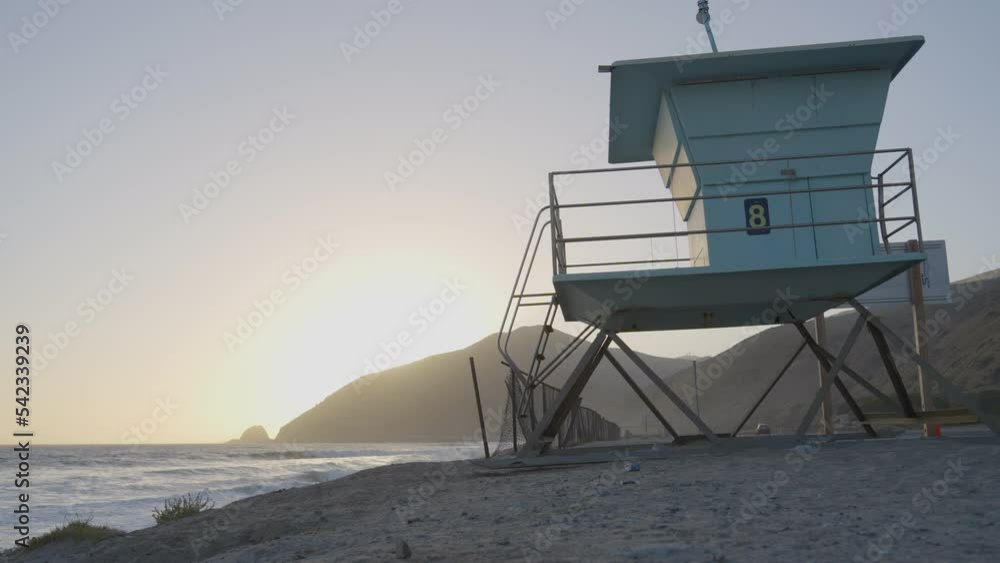 panning shot of lifeguard tower at an empty Mondo's Beach as the sun sets behind a distant mountain
located in Southern California. panning shot of lifeguard tower at an empty Mondo's Beach as the sun sets behind a distant mountain
located in Southern California.