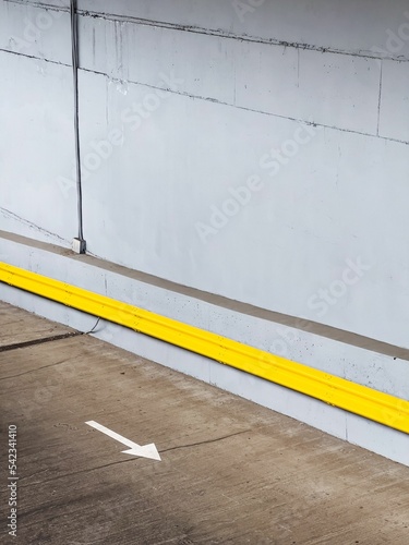 Vertical shot of white arrow on the ground of a parking garage indicating which side to go