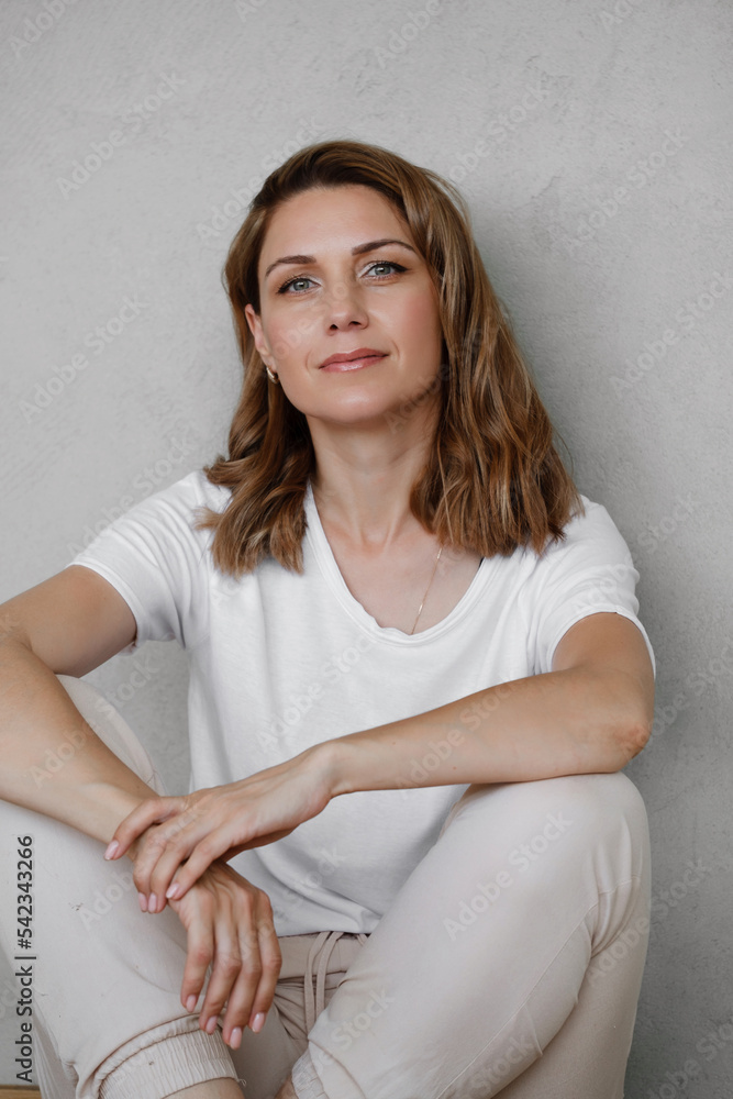 Closeup portrait of happy creative young woman smiling and looking directly to the camera over grey wall. Female at her 40s relaxed in white t-shirt Closeup portrait of happy creative young woman smiling and looking directly to the camera over grey wall. Female at her 40s relaxed in white t-shirt