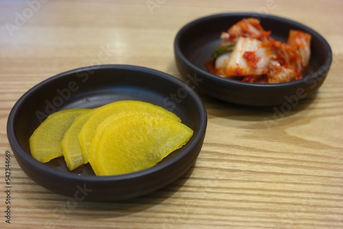 Pickled radish and kimchi are served as side dishes on a round plate.