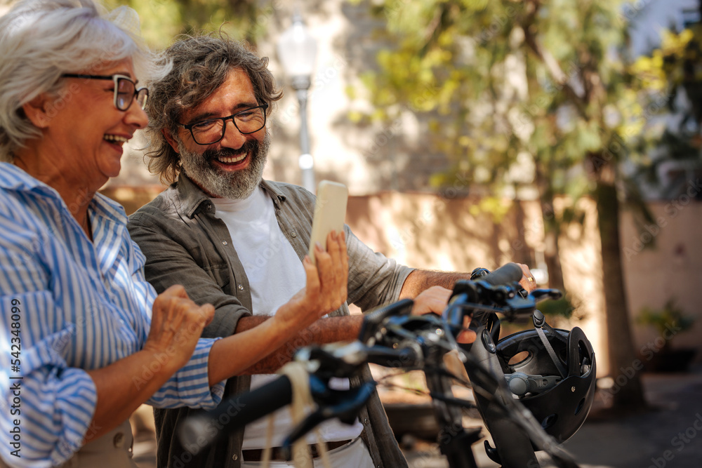 Obraz premium Senior couple use cellphone outside.