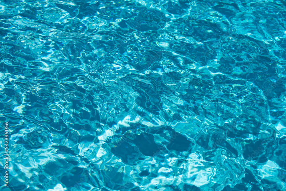 Background of blue water in swimming pool with sun reflection, ripple water wave in pool. Clear water background.