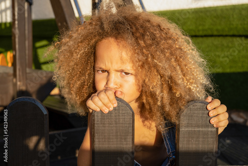 Photography Portrait of a little angry little girl on the background of a summer playground
