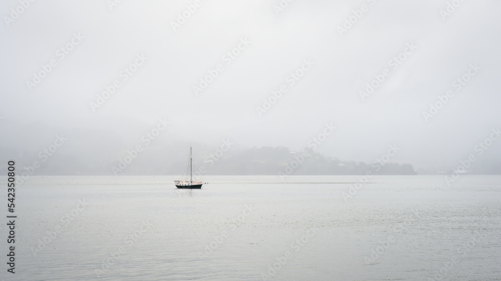 Yacht in heavy fog at Otago Peninsula. Image of minimalist photography.