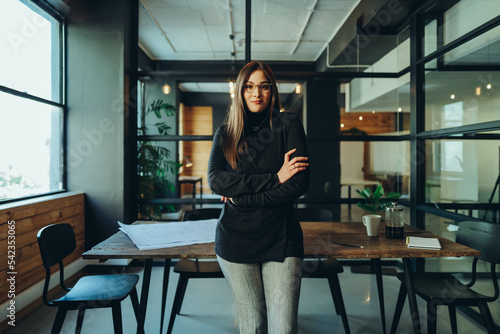 Confident young businesswoman standing in a boardroom