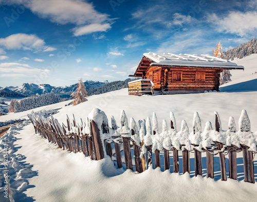 Snowy winter scene of Dolomite Alps. Wooden chalet on the hill of Alpe di Siusi village. Bright landscape of ski resort, Ityaly, Europe. Beauty of nature concept background. photo