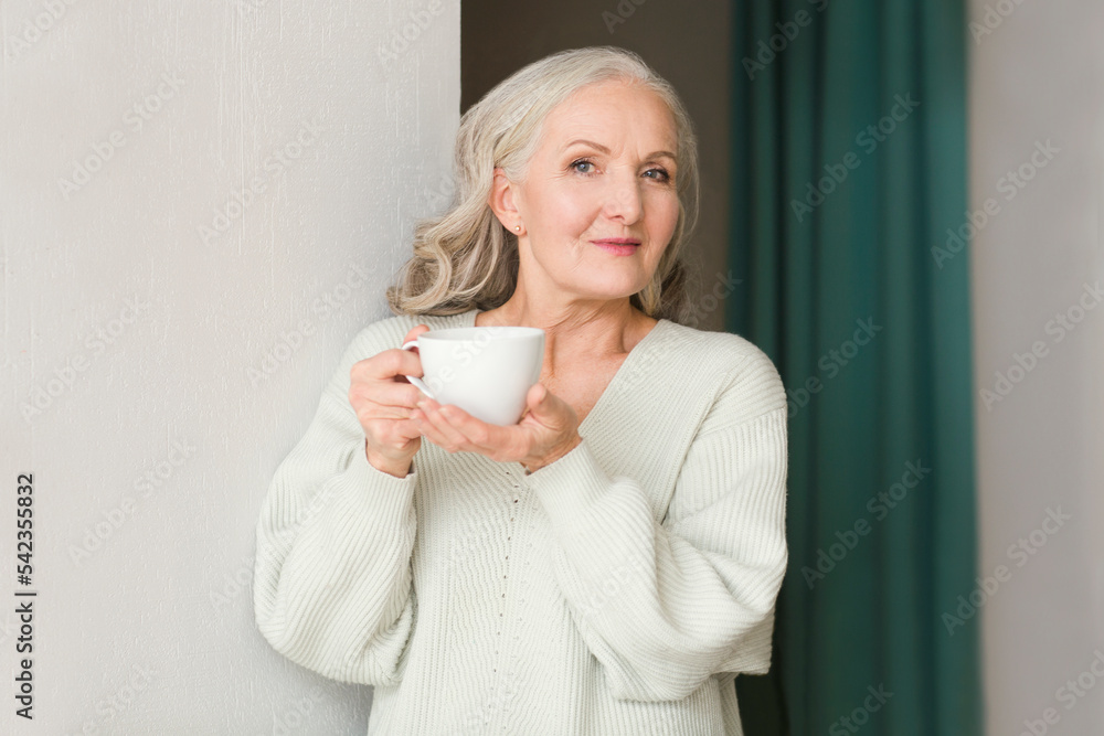 senior woman with gray hair drinks tea in the kitchen at home. concept without stress. mental health. Slow life. Enjoying the little things senior woman with gray hair drinks tea in the kitchen at home. concept without stress. mental health. Slow life. Enjoying the little things