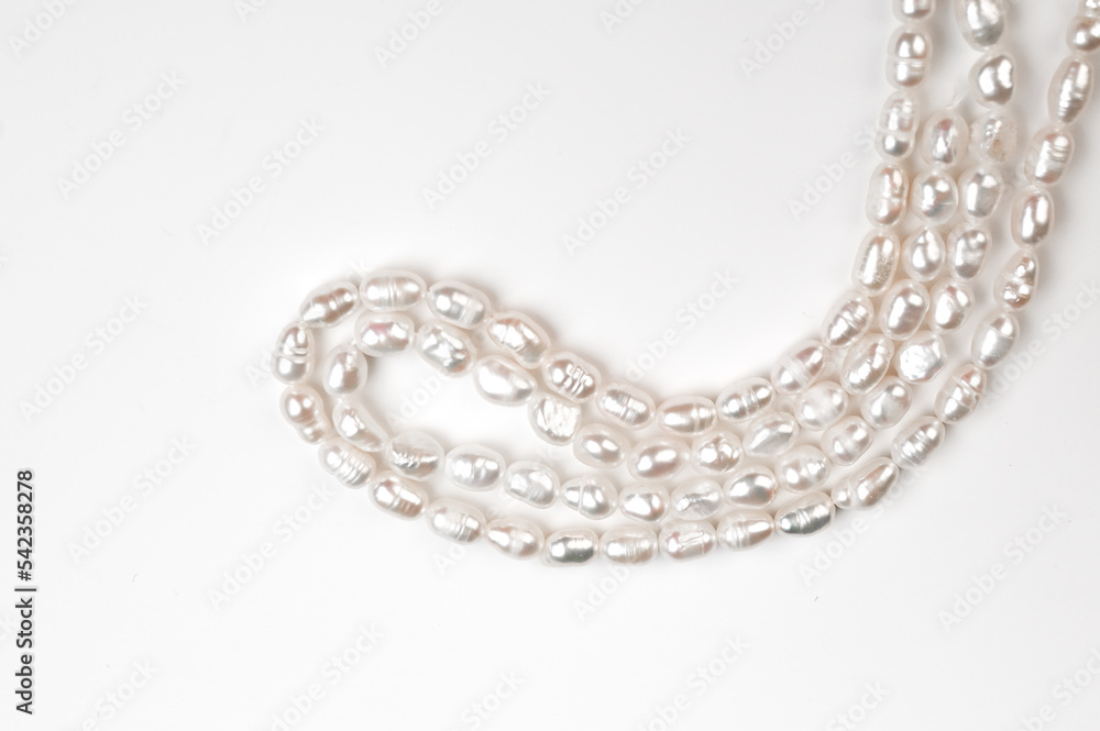 Natural freshwater round pearl beads on white background. String of pearls top view Natural freshwater round pearl beads on white background. String of pearls top view