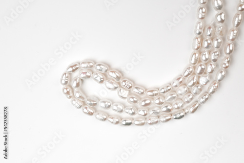 Natural freshwater round pearl beads on white background. String of pearls top view