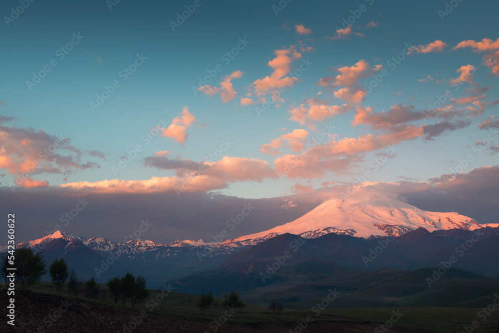Elbrus mount with pink clouds at sunrise. View from Gil-Su valley in North Caucasus, Russia