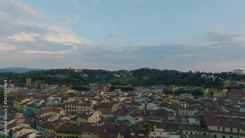 Forwards fly above old town development, historic houses in city centre at twilight. Florence, Italy