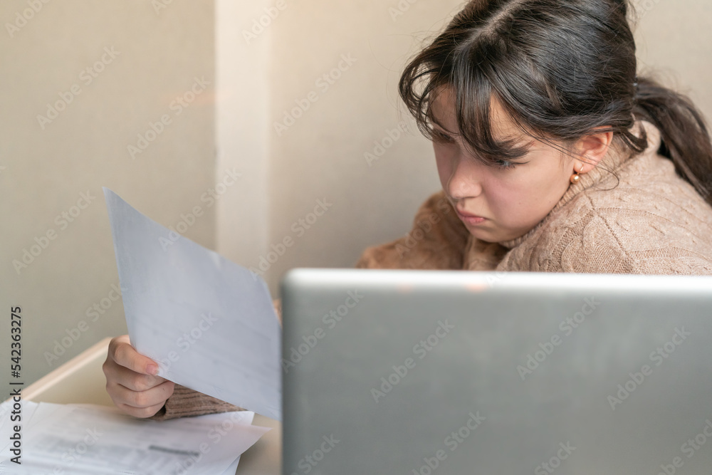 girl works with documents sitting in front of a laptop at her desk girl works with documents sitting in front of a laptop at her desk