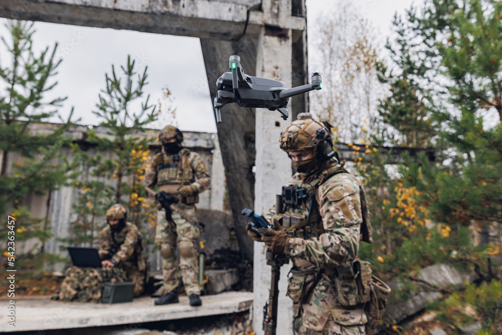 Modern army soldiers using aerial drone for artillery guidance and scouting view enemy positions in military operation Modern army soldiers using aerial drone for artillery guidance and scouting view enemy positions in military operation