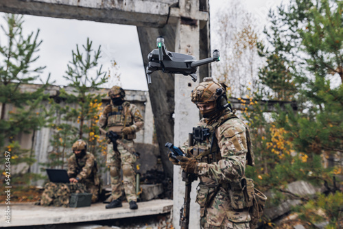 Modern army soldiers using aerial drone for artillery guidance and scouting view enemy positions in military operation