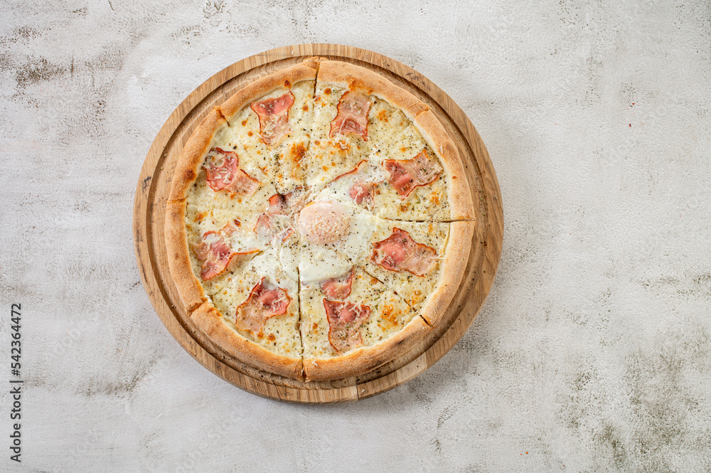 Fresh pizza carbonara with ham and scrambled egg on the concrete background