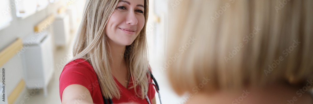 Smiling female doctor keeps hand on patient shoulder Smiling female doctor keeps hand on patient shoulder