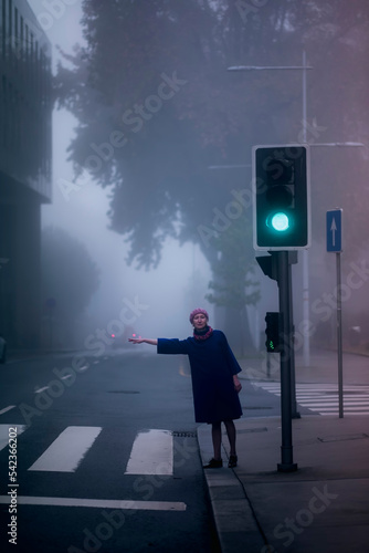 A woman in a blue coat votes in the street in a thick fog.