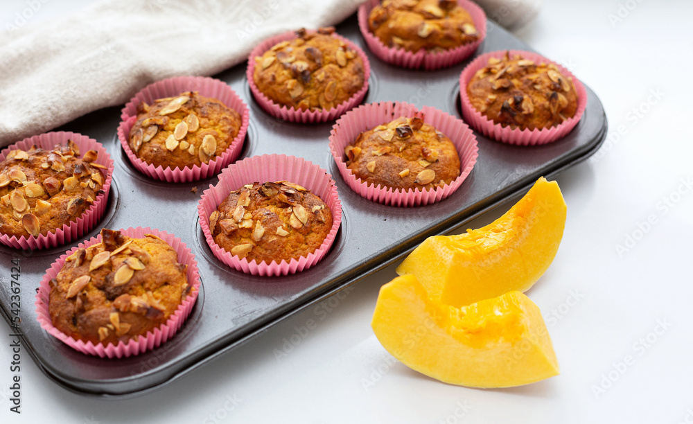 Homemade pumpkin muffins with pumpkin seeds and walnut pieces. Fall baking for Thanksgiving and Halloween. Cupcakes in baking dish on linen napkin. Selective focus. Close up. Homemade pumpkin muffins with pumpkin seeds and walnut pieces. Fall baking for Thanksgiving and Halloween. Cupcakes in baking dish on linen napkin. Selective focus. Close up.