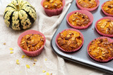 Homemade pumpkin muffins with pumpkin seeds and walnut pieces. Fall baking for Thanksgiving and Halloween. Cupcakes in baking dish on linen napkin. Selective focus. Top view. Close up