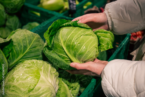 A woman chooses cabbage in a grocery store, close-up.