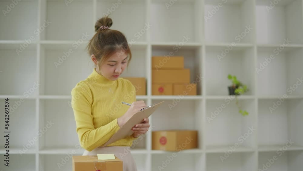 Young owner business woman received orders from clients and preparing products in parcel cardboard box packaging at home. Young owner business woman received orders from clients and preparing products in parcel cardboard box packaging at home.