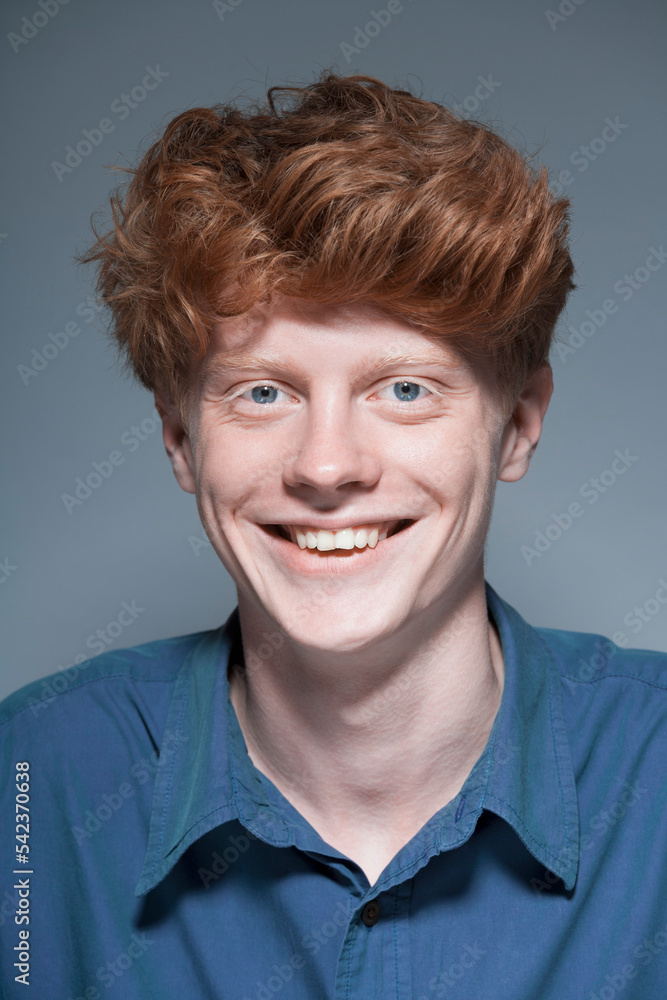 Portrait of young man against grey background, smiling Portrait of young man against grey background, smiling