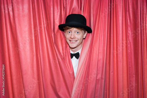 Germany, Young magician behind curtain, smiling photo