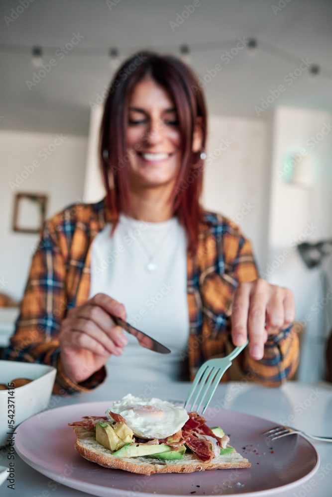 Woman smiling while eating an avocado toast in a cafe or restaurant. Woman smiling while eating an avocado toast in a cafe or restaurant.
