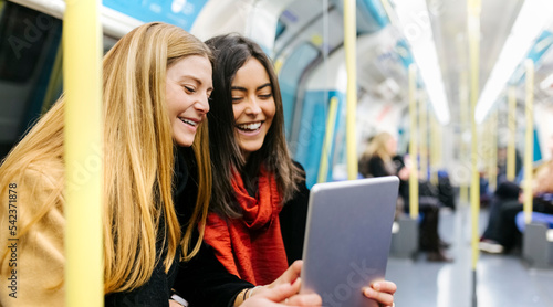UK, London, Two young women in the underground using digital tablet photo