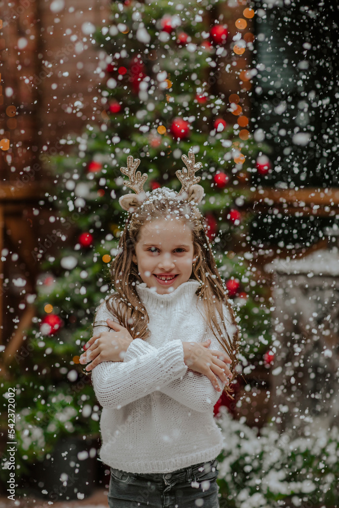 Smiling girl standing under snowfall in front yard Smiling girl standing under snowfall in front yard