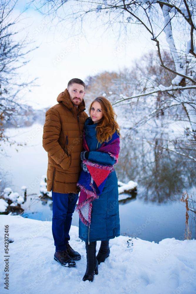 A young couple walks in a snowy park in winter and warms up with tea. The beauty of nature before the New Year. Copy space