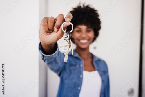 Happy woman showing house keys standing in front of door photo