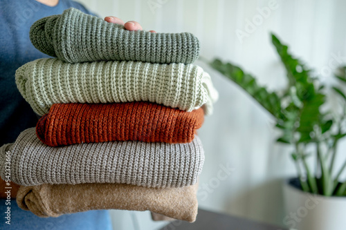 Man holding woolen sweaters at home photo